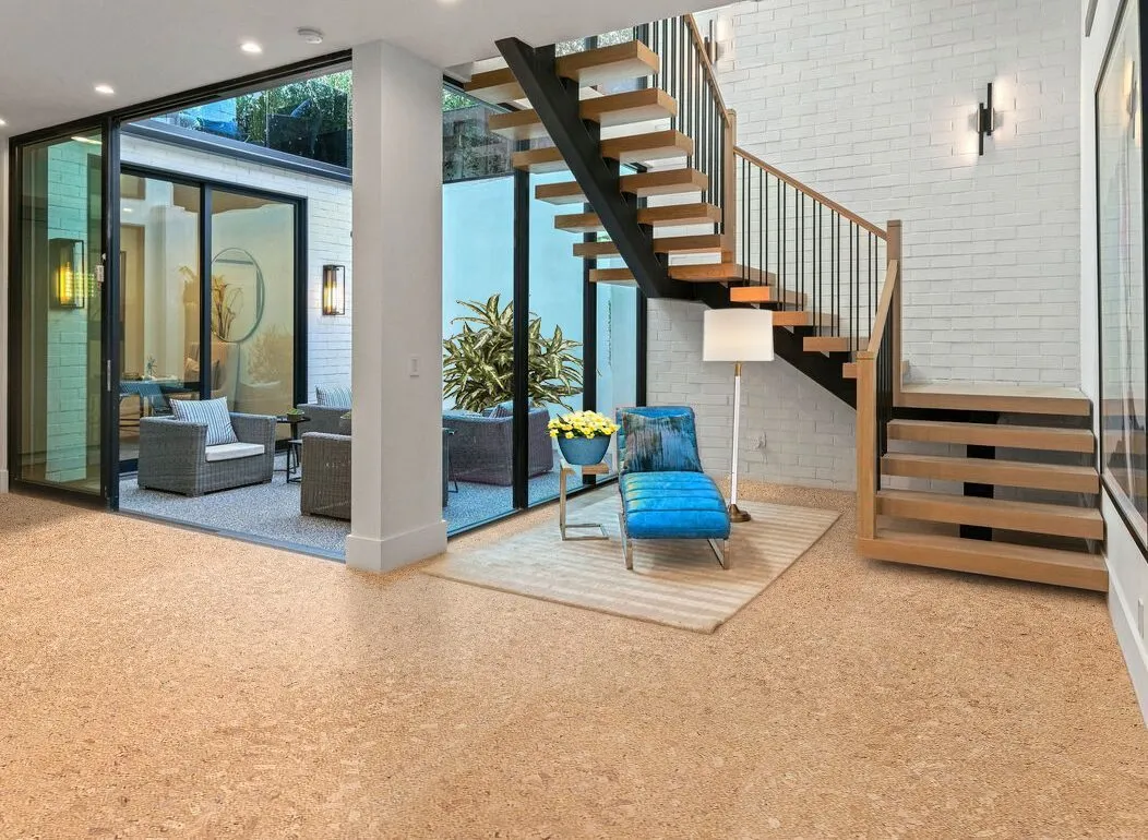 Natural cork flooring in a sunlit living space with a timber staircase and blue armchair.