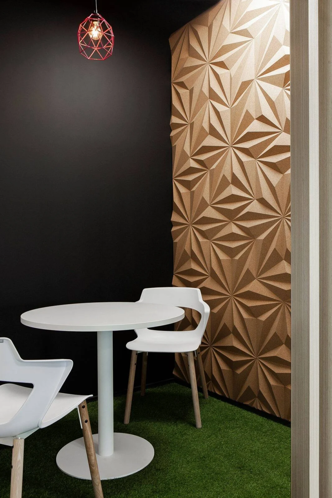 Geometric cork panels beside a café table and white chairs.