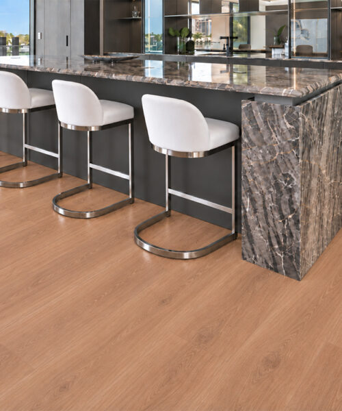 Warm wood-grain American Red Oak cork flooring complements a waterfront kitchen with a marble waterfall island.