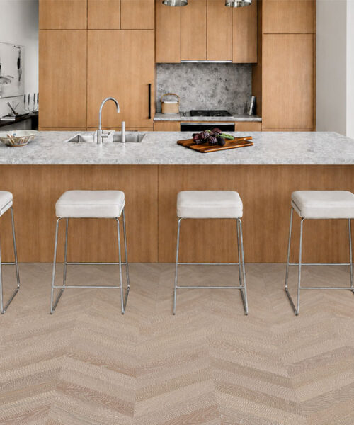 Aurora Chevron Swiss Design Cork Floating Flooring Complements A Modern Kitchen With A Stone Island And Wood Cabinets.