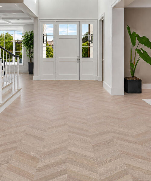 Aurora Chevron Sustainable Cork Flooring Extends Through A Bright Foyer Beside A Staircase And Sitting Area.