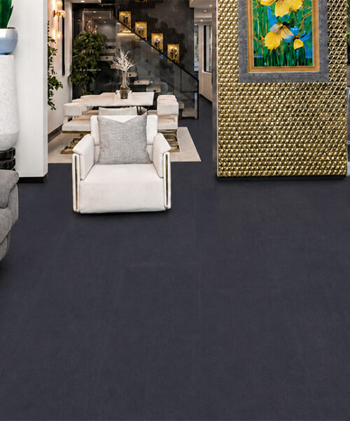Luxury Black Buffalo Leather Flooring In An Upscale Lounge With Dark Textured Planks, Gray Sofa, White Accent Chair, Fireplace And Decorative Feature Walls.