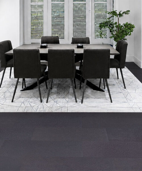 Ustainable Black Buffalo Leather Flooring Surrounding A Geometric Area Rug In A Modern Dining Room With Black Chairs And Bright White Interiors.