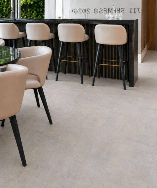 Bris Stone light gray stone-look cork flooring extends between a modern home bar, dining table, and staircase.