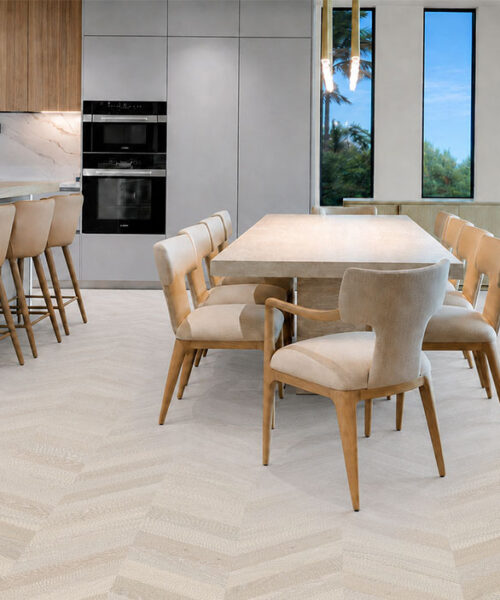 Clara Chevron Sustainable Cork Flooring Extends Through A Modern Kitchen And Dining Room With Beige Seating.