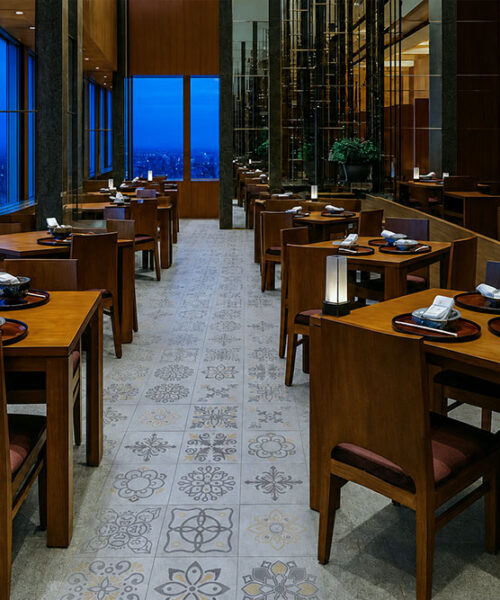 Light Gray Classic Porcelain Swiss Techslate Commercial-Grade Flooring With Decorative Medallion Prints Complements A Warmly Furnished Restaurant Dining Room.