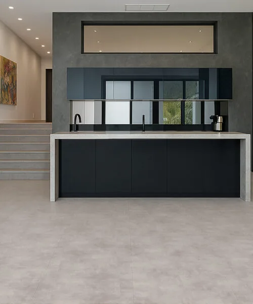 Copperstone Gray Swiss-Made Flooring Features A Muted Stone Pattern In A Contemporary Kitchen With Black Cabinetry And Staircase.