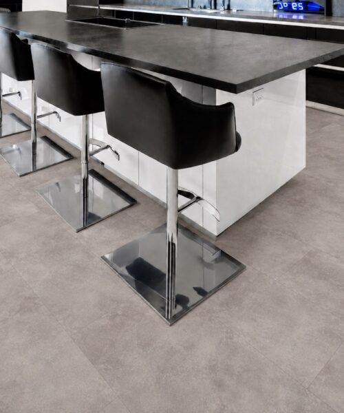 Copperstone Gray Natural Composite Flooring With Soft Concrete-Look Texture Surrounds A Contemporary Kitchen Island With Black Barstools.