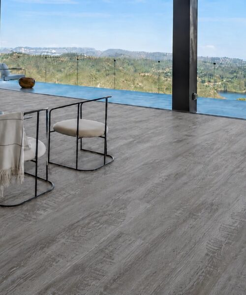 Earthy Pine Wood-Look Natural Composite Flooring With Gray-Brown Grain In A Modern Living Room Overlooking Hills.