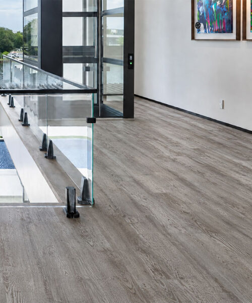 Earthy Pine commercial-grade Natural Composite Flooring with muted gray wood grain in a contemporary gallery hallway.