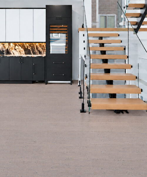 Gray Bamboo warm gray cork floor planks span a modern entryway with black cabinets and open staircase.