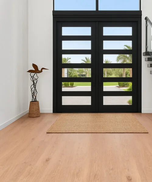 Open Entryway With Honey Oak Forna Natural Composite Flooring And Large Black Double Doors.