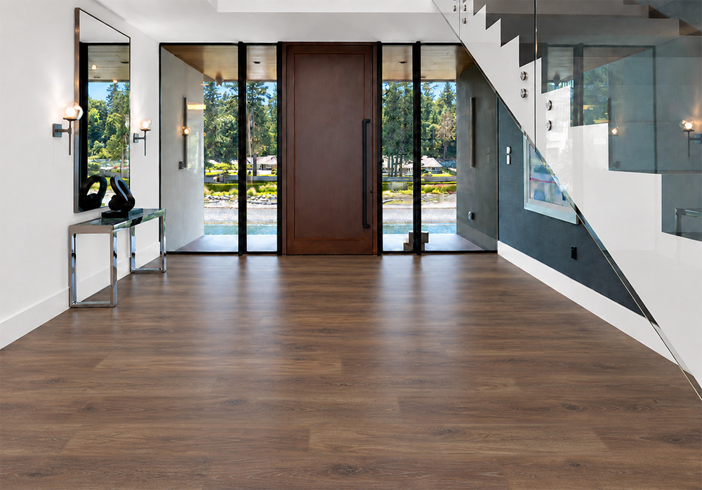 Latte - 7/16&Quot; (11Mm) - Swiss Design Cork Floating (Flat11) Comfortable Latte Wood-Grain Cork Floating Flooring In A Modern Entryway With A Glass Staircase, Wood Front Door, And Floor-To-Ceiling Windows.