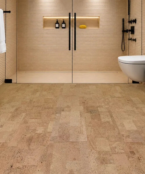 Leather Natural 6mm glue-down cork tile flooring in a luxury bathroom with a frameless glass shower, modern black vanity, and sealed natural cork floor.
