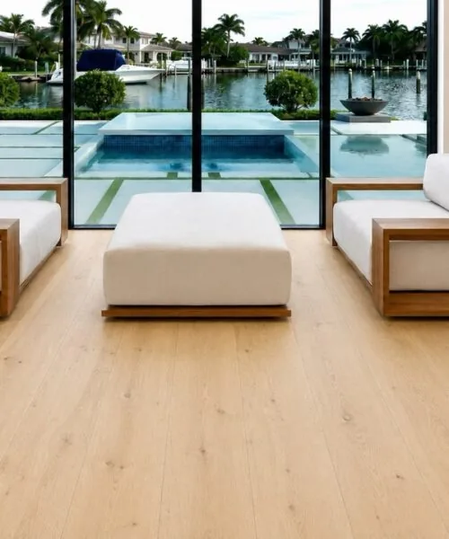 Uxury Living Room With Long Beach Swiss Design Cork Floating Flooring, Modern Sofas, And Floor-To-Ceiling Windows Overlooking A Waterfront Pool.