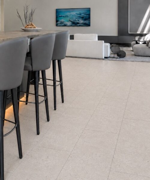 Matera Blend - 19/64&Quot; (7.5Mm) - Swiss Techslate (Mmatbd7.5) Light Limestone Matera Blend Stone-Look Flooring Extends Beneath A Kitchen Island And Into A Modern Living Room.