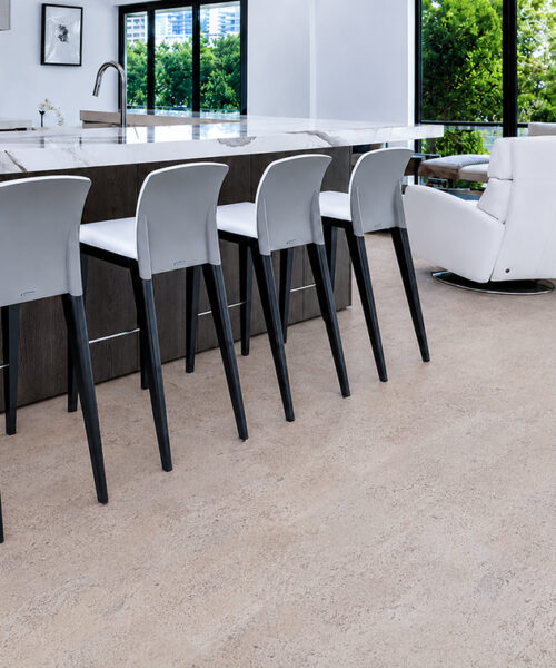 Mystic Vanilla Swiss Real Cork Floating Flooring in an open-plan kitchen with a marble island and bar stools.