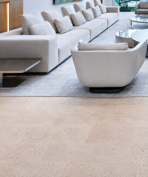 Mystic Vanilla Swiss Real Cork Floating Flooring Beside A White Sectional Sofa In A Modern Luxury Living Room.