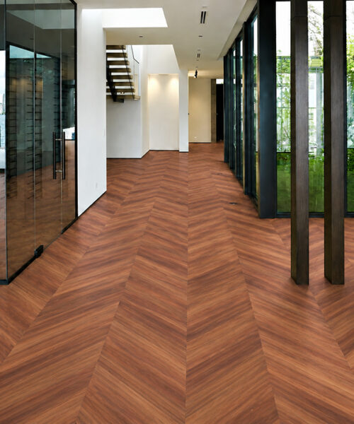 Noble Chevron Walnut Floating Cork Flooring Extends Through A Modern Entryway With Glass Walls And Dark Columns.