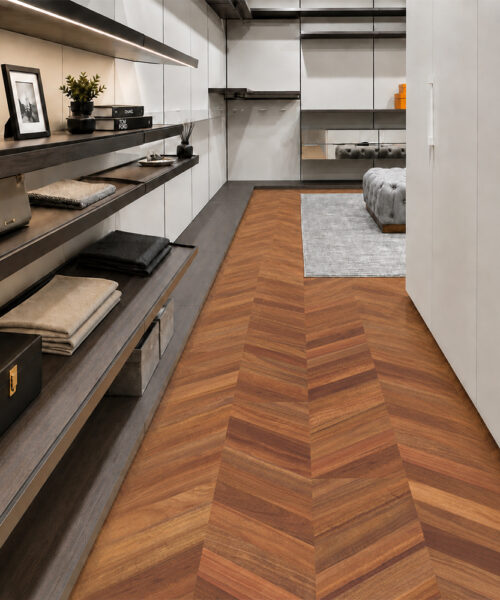 Noble Chevron Sustainable Cork Flooring Forms A Warm Walnut Pattern Through A Walk-In Closet With Dark Shelving.