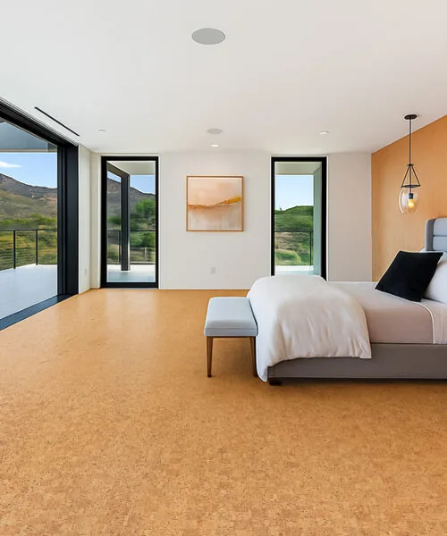 Serene bedroom with large windows and mountain views, featuring Quodro Swiss cork flooring and warm accent wall.
