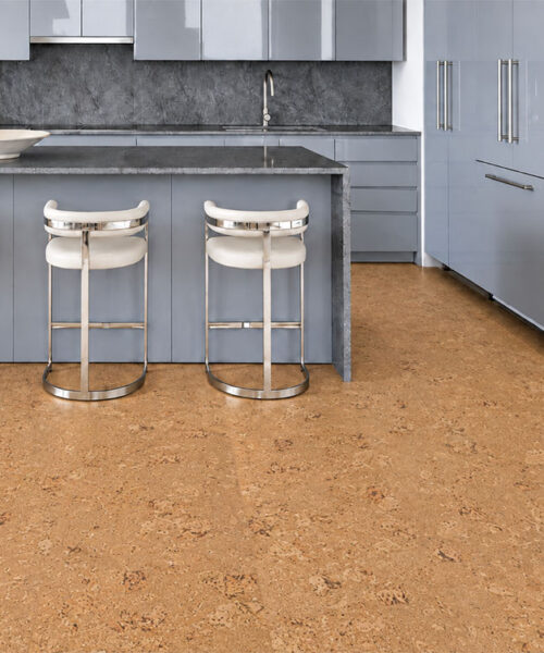 Salami gold-oak cork floor planks complement a gray kitchen with stone island and white stools.