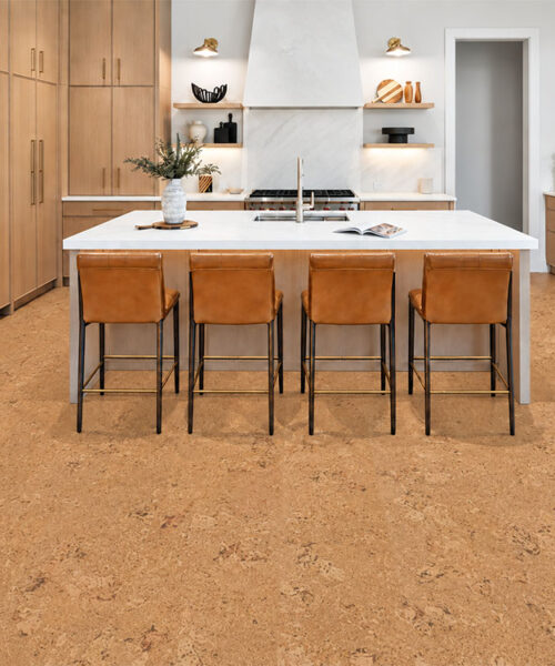 Salami 12mm floating cork flooring grounds a light-wood kitchen with white island and leather stools.