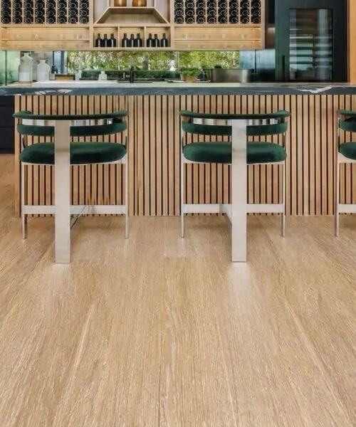 Sandstorm Swiss Design Cork Floating Flooring In A Contemporary Home Bar With Natural Light Oak Wood Grain, Wood Slat Bar Front, And Modern Seating.