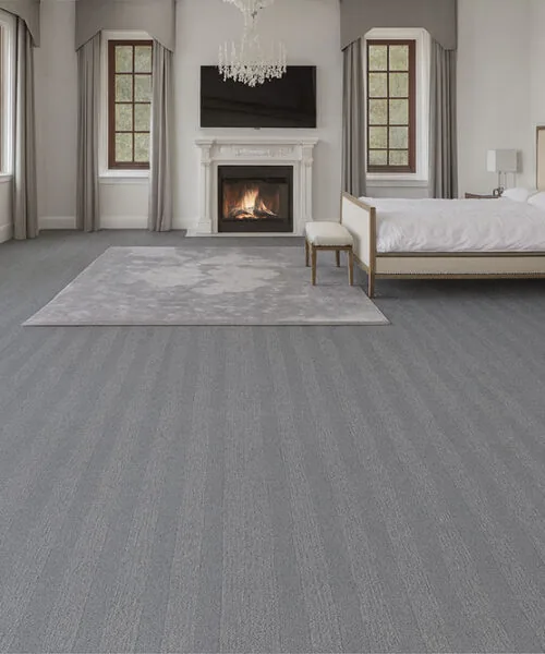 Elegant Bedroom With Serpent Luxe Forna Swiss Leather Floating Flooring, Gray Patterned Design Adding Modern Luxury Under A Cozy Fireplace Setting.