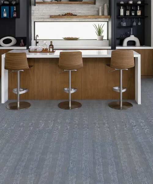 Contemporary Kitchen Bar With Serpent Luxe Forna Swiss Leather Flooring, Textured Gray-Blue Floating Planks Enhancing Wood Cabinetry And Modern Stools