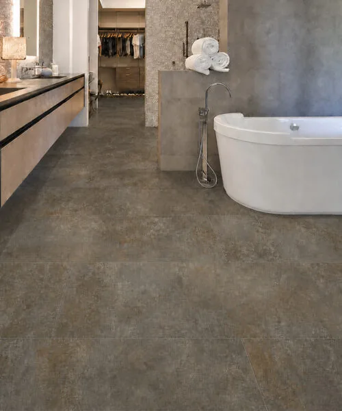 Sunlit Stone - 19/64&Quot; (7.5Mm) - Swiss Techslate (Msunst7.5) Sunlit Stone Swiss Techslate Brown-Gray Stone-Look Flooring In A Luxury Bathroom With A Freestanding Bathtub.