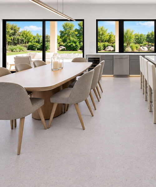 Sustainazzo Light Gray Speckled Cork Flooring In A Modern Kitchen-Dining Room With A Marble Island.