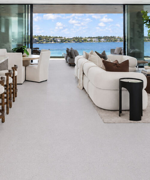 Sustainazzo light gray terrazzo-look cork flooring extends through a waterfront open-plan kitchen and living room.