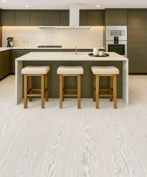 Open-Concept Kitchen Highlighted By Swiss Snow Cap Real Wood Floating Flooring, Contrasting With Dark Cabinetry And A Light Stone Island.