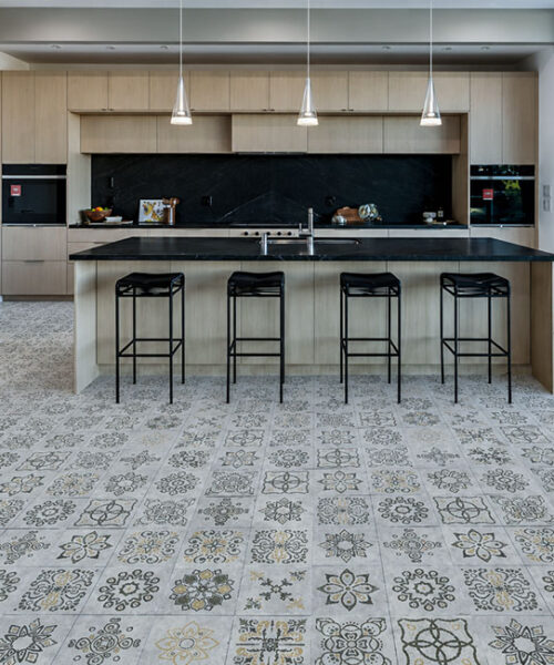 A Modern Kitchen With Bar Seating Showcases Light Gray Classic Porcelain Techslate Flooring With Intricate Floral And Geometric Prints.